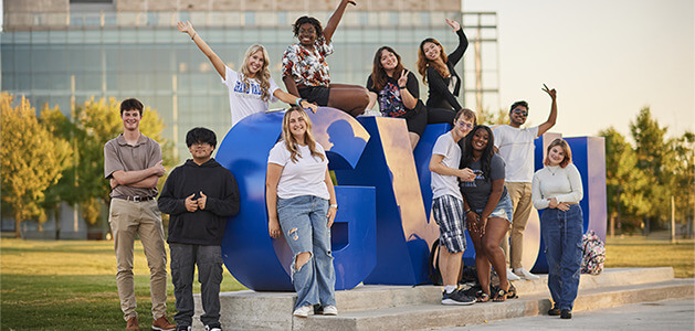 Students pose for a photo around a large GVSU statue on the Allendale campus